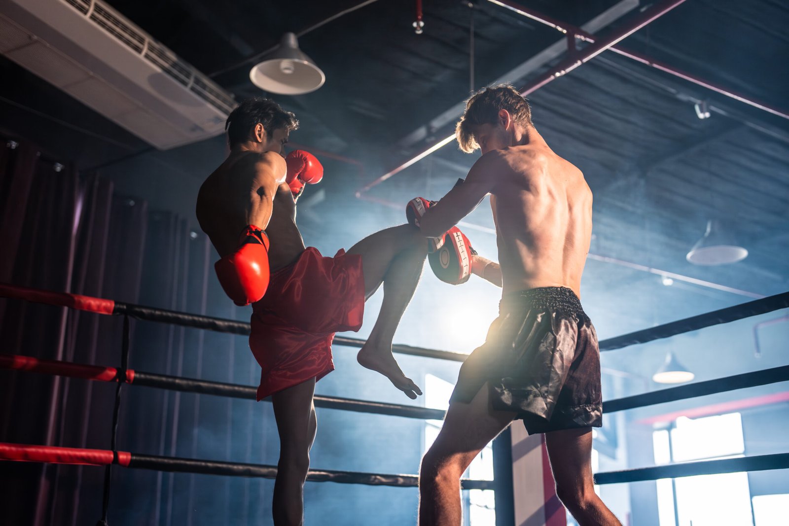 Two young professional boxer having a competition tournament on stage. Attractive male athlete fighters muscular shirtless punches and hitting competitor enjoy boxing exercise in the ring at stadium.